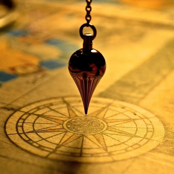 A pendulum swings over an old map with a compass rose.