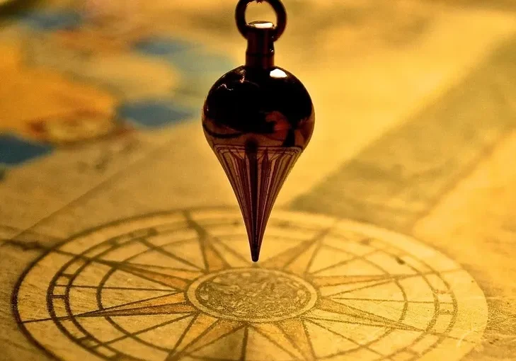 A pendulum swings over an old map with a compass rose.